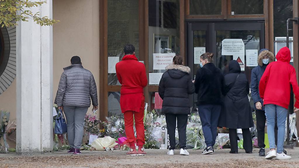 Schüler gedenken vor einer Schule dem Lehrer, der bei einer mutmaßlich terroristisch motivierten Tat ermordet wurde.