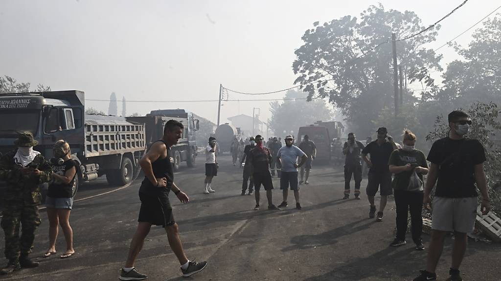 Verunsicherte Anwohner auf einer Straße in Nea Anchialos. Wegen der starken Rauchbildung flüchteten viele Urlauber an den örtlichen Strand. Foto: Tatiana Bolari/Eurokinissi/AP/dpa
