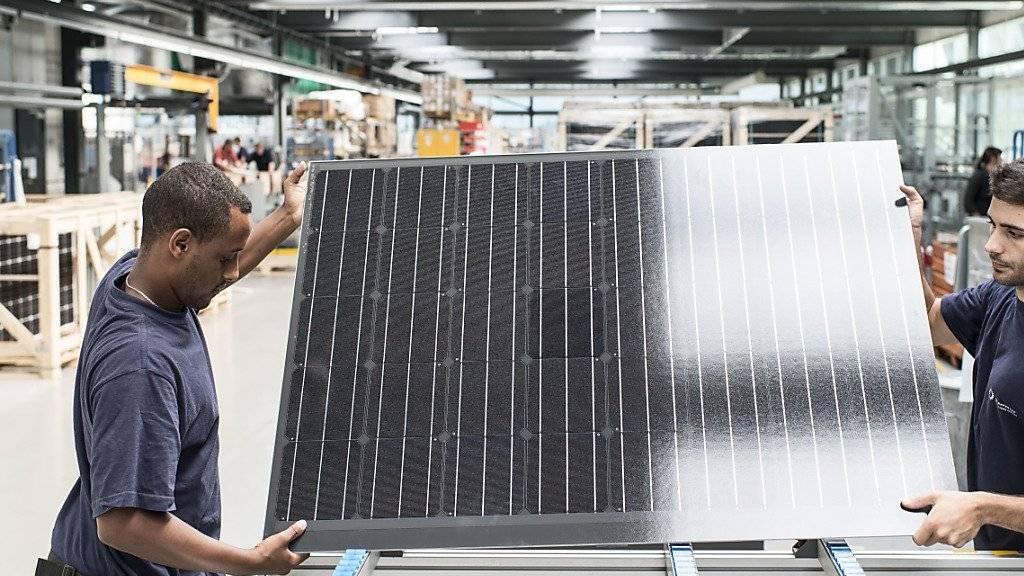 Zwei Mitarbeiter bereiten ein Solarpanel zur Verpackung vor bei Meyer Burger - das Unternehmen schreibt auch 2015 Verlust. (Archivbild)