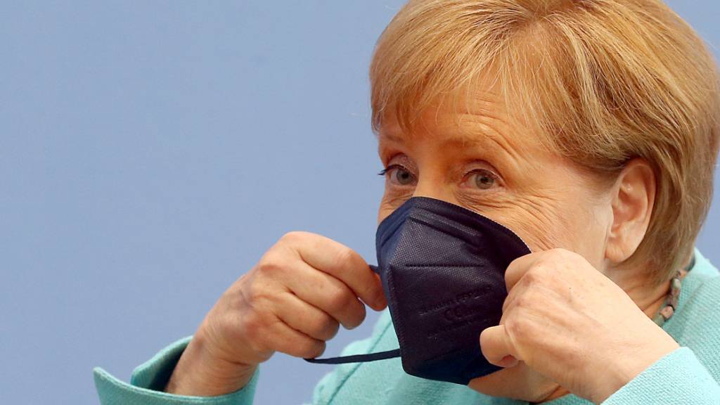 Bundeskanzlerin Angela Merkel (CDU) setzt sich ihre Maske auf. Foto: Wolfgang Kumm/dpa