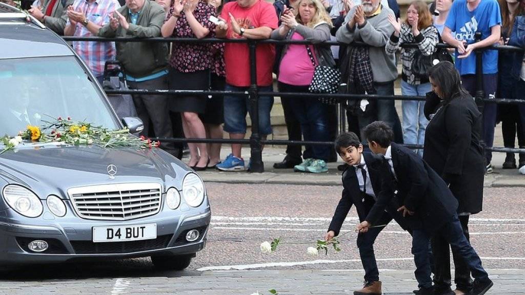 Kinder werfen Blumen vor das Auto mit dem Sarg der Labour-Abgeordneten Jo Cox.