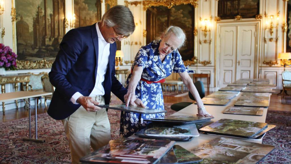 HANDOUT - Die dänische Königin Margrethe II. und Bille August, Regisseur, schauen sich Fotos an. Die Monarchin sorgt beim neuen Netflix-Streifen «Ehrengard», der auf einem Buch der dänischen Autorin Blixen basiert, für Bühnenbild und Kostüme. Foto: Jacob Joergensen/JJ Film/Netflix/dpa - ACHTUNG: Nur zur redaktionellen Verwendung im Zusammenhang mit einer Berichterstattung über den Film und nur mit vollständiger Nennung des vorstehenden Credits