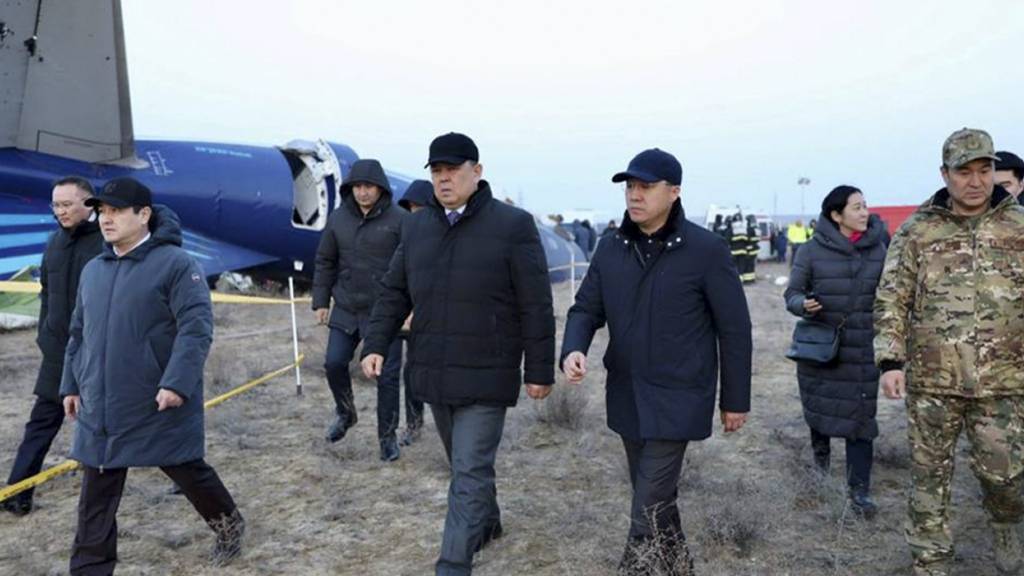 HANDOUT - Mitglieder einer Untersuchungskommission und örtliche Beamte gehen am Wrack der Embraer 190 von Azerbaijan Airlines vorbei. Foto: Uncredited/The Administration of Mangystau Region/AP/dpa