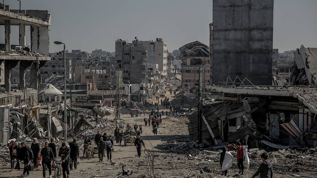 Palästinenser gehen nach dem Rückzug der israelischen Armee aus dem Norden des Gazastreifens neben beschädigten Gebäuden zurück in ihre Häuser. Foto: Omar Ishaq/dpa