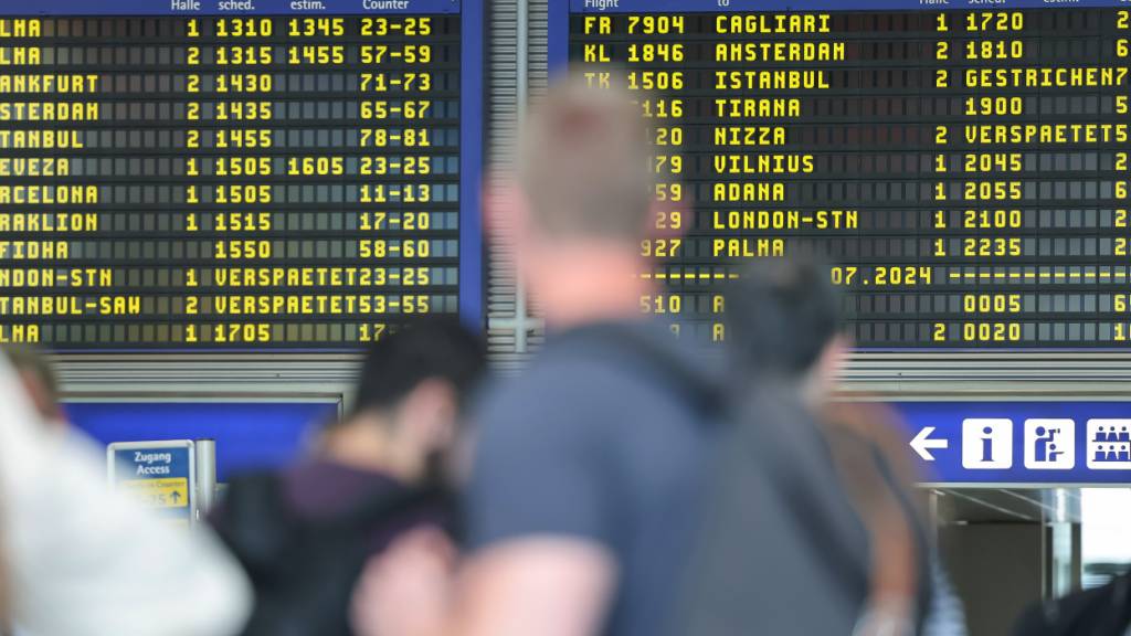 ARCHIV - Reisende warten vor der Anzeigentafel am Nürnberger Flughafen, die verspätete oder gestrichene Flüge anzeigt. Weltweite Probleme in den Computersystemen störten damals auch An - und Abflüge am Nürnberger Flughafen. Foto: Daniel Löb/dpa