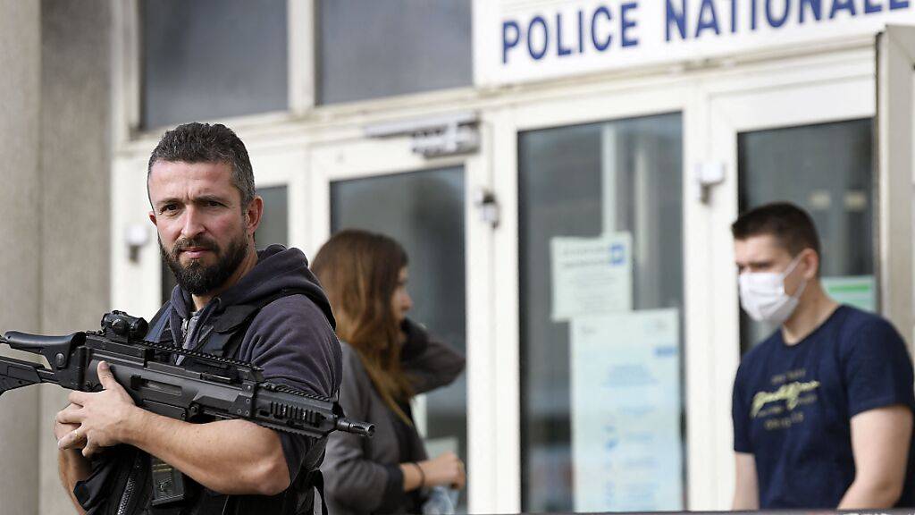 Ein bewaffneter Polizist steht vor dem Eingang zu einer Polizeistation, nachdem ein Mann einen Polizisten mit einer Stichwaffe angegriffen hat. Foto: Nicolas Tucat/AFP/dpa