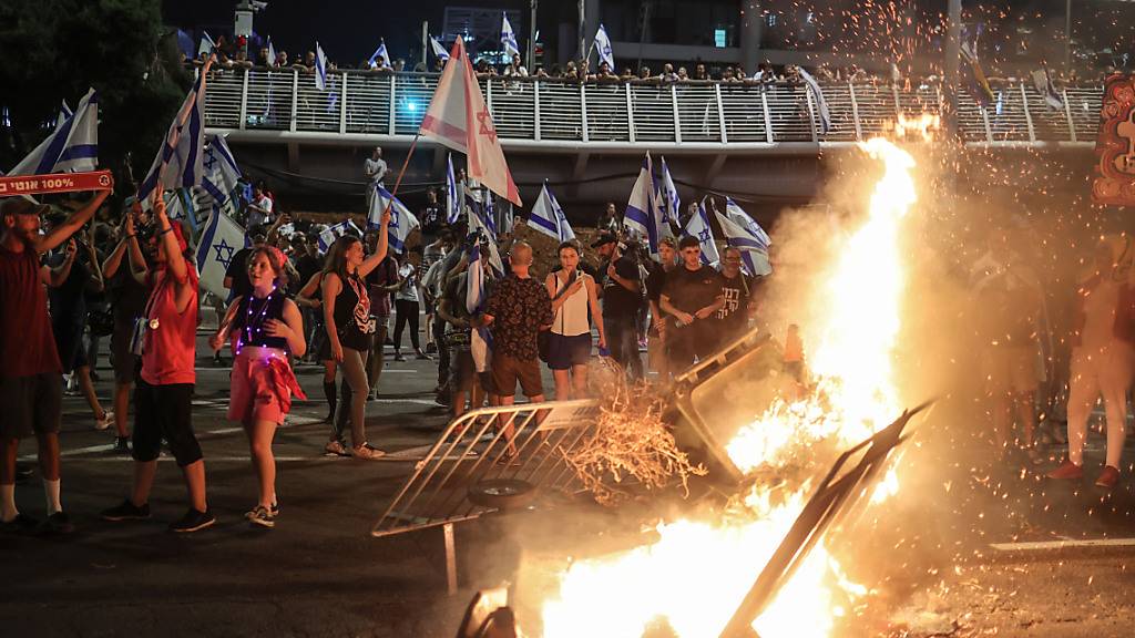 Israelische Demonstranten verbrennen Gegenstände während einer Protestaktion in Tel Aviv. Foto: Ilia Yefimovich/dpa