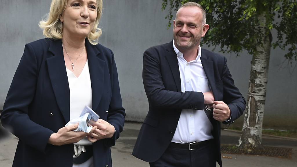 Marine Le Pen, Parteivorsitzende der Rassemblement National,  und der lokale Kandidat Steeve Briois gehen nach der Stimmabgabe bei den Regionalwahlen. Foto: Uncredited/AP/dpa