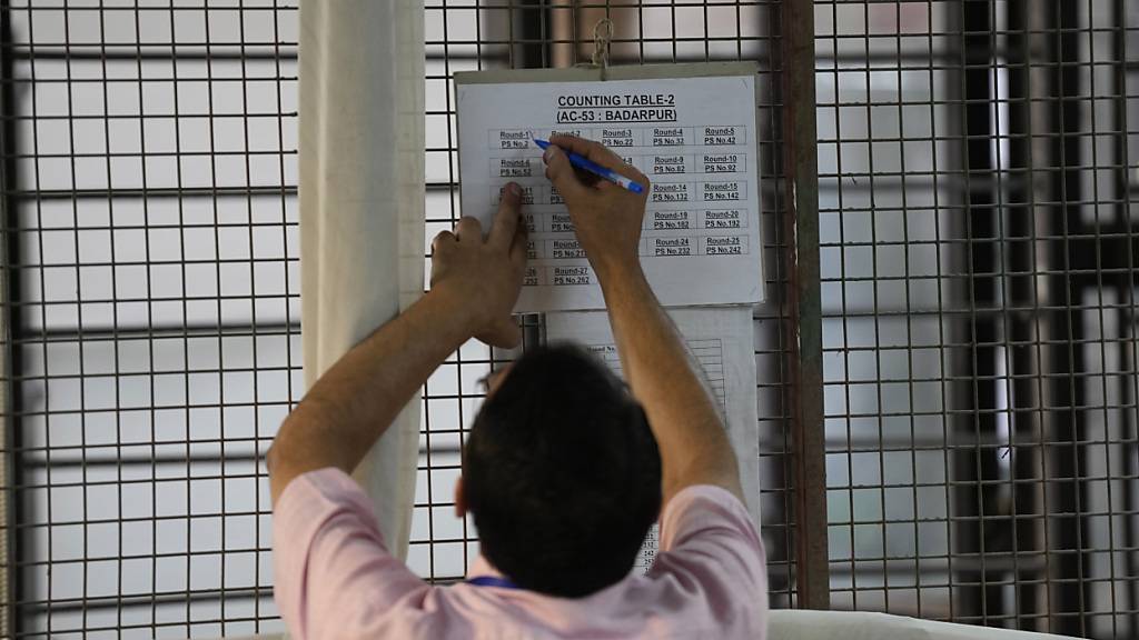 Ein Wahlhelfer markiert eine Tabelle nach der ersten Runde der Stimmenauszählung in einem Auszählungszentrum in Neu-Delhi, Indien. Foto: Manish Swarup/AP/dpa