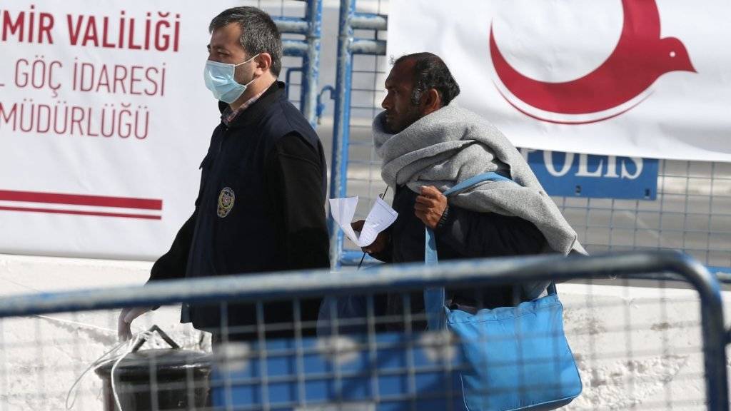 Ein türkischer Polizist (links) nimmt im Hafen von Izmir einen Mann in Empfang, der mit der Fähre von Lesbos gekommen ist.