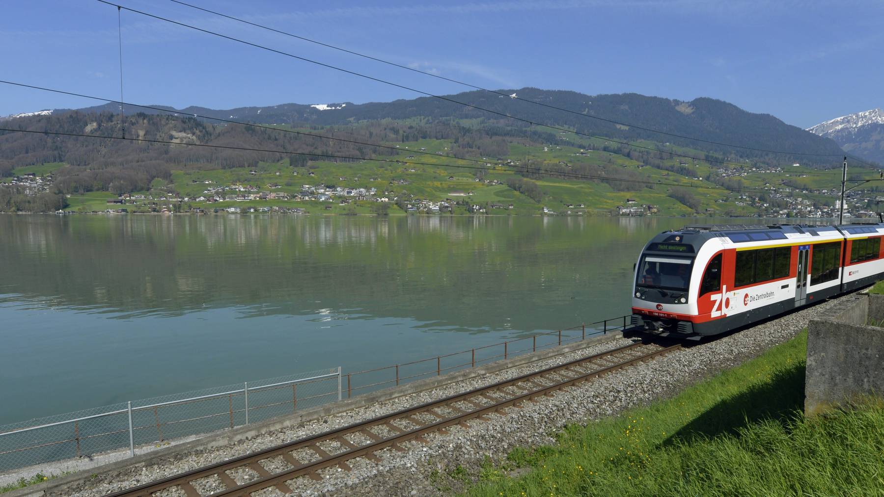 Ein Zug der Zentralbahn fährt durch die Landschaft des Sarnersees im Kanton Obwalden auf der Brünigstrecke.