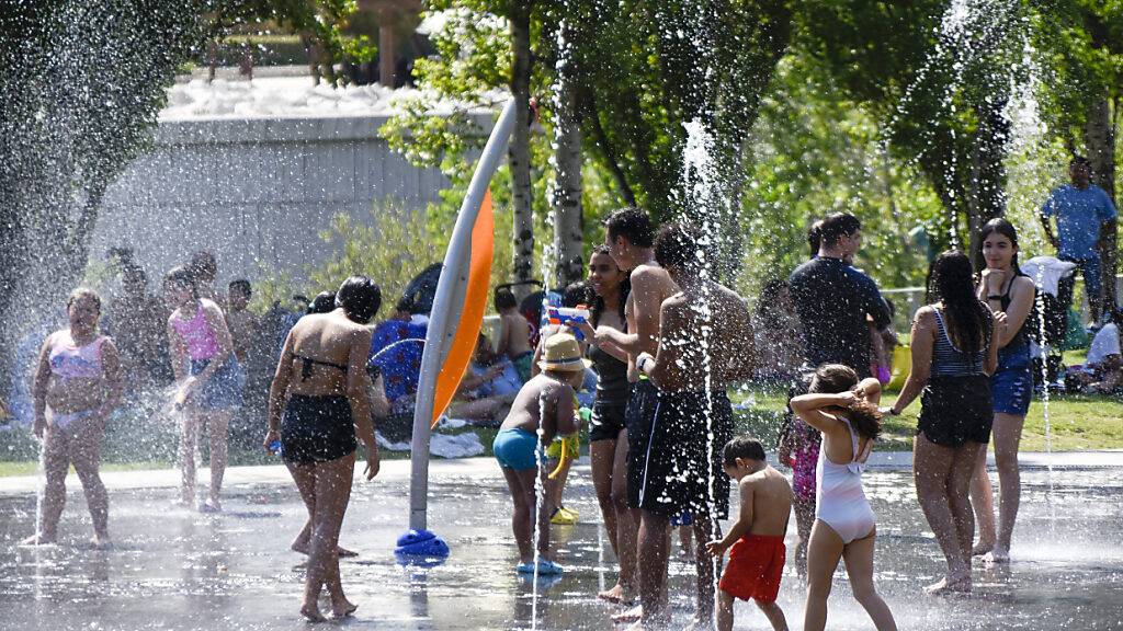 ARCHIV - Menschen kühlen sich in dem Wasser auf einem Fontänenfeldes des künstlichen Strandes im Madrid Rio Park ab. Foto: Richard Zubelzu/ZUMA Press Wire/dpa