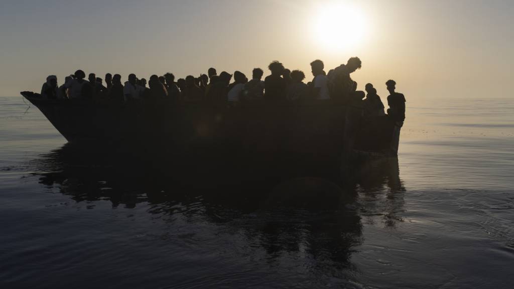 ARCHIV - Migranten sitzen in einem Holzboot, während sie von Freiwilligen des Rettungsschiffs Ocean Viking gerettet werden. Foto: Jeremias Gonzalez/AP/dpa