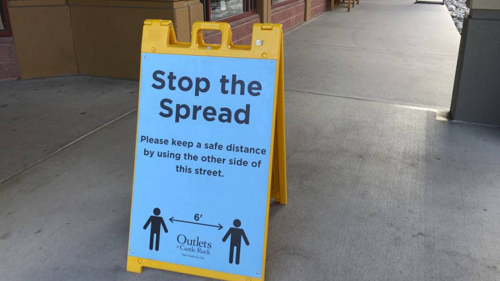 Ein Schild vor einem Einkaufszentrum weist Kunden darauf hin, Abstand zu halten, um die Verbreitung des Coronavirus einzudämmen.