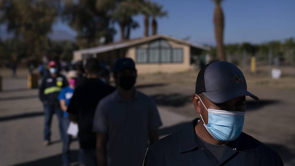 Eingewanderte Landarbeiter tragen Mund-Nasen-Bedeckungen und warten in einer Schlange, um die Corona-Impfung zu erhalten. Verbände warnen davor, dass Millionen Einwanderer zu den am schwierigsten zu erreichenden Menschen während der größten Impfkampagne in den USA gehören könnten. Foto: Jae C. Hong/AP/dpa