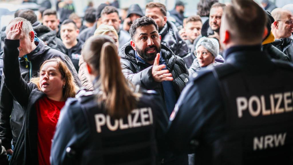 dpatopbilder - Aufgebrachte Kunden diskutieren vor der Sparkassenfiliale in Buer mit Polizeibeamten nach der Räumung des Vorraums der Filiale. Foto: Christoph Reichwein/dpa - ACHTUNG: Nur zur redaktionellen Verwendung im Zusammenhang mit der aktuellen Berichterstattung und nur mit vollständiger Nennung des vorstehenden Credits