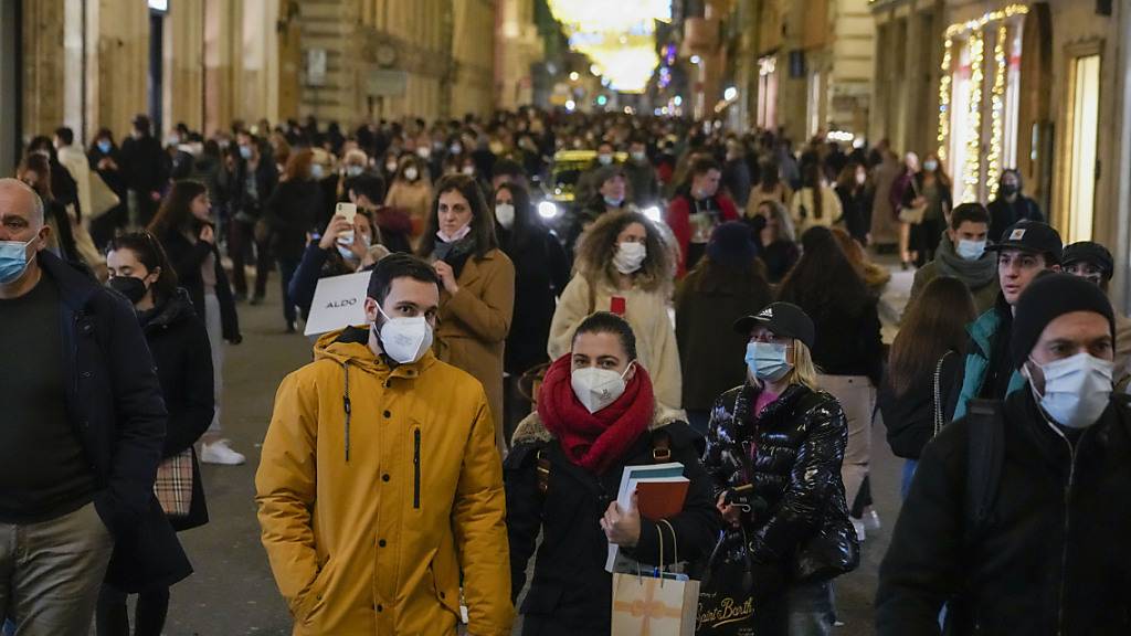 Menschen gehen durch eine Einkaufsstraße in Rom. Foto: Andrew Medichini/AP/dpa