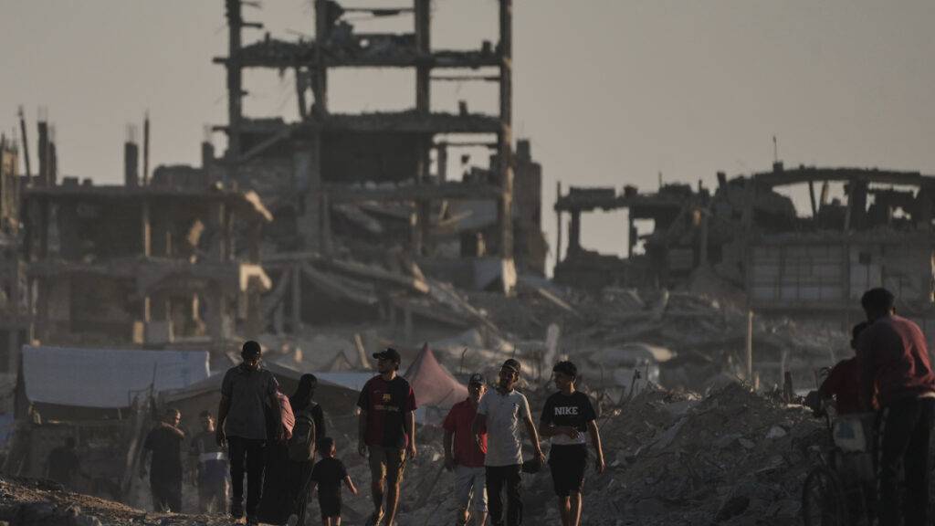 Palästinenser gehen in der Stadt Gaza zwischen den Trümmern von Gebäuden umher, die durch israelische Luftangriffe zerstört wurden. Foto: Jehad Alshrafi/AP/dpa