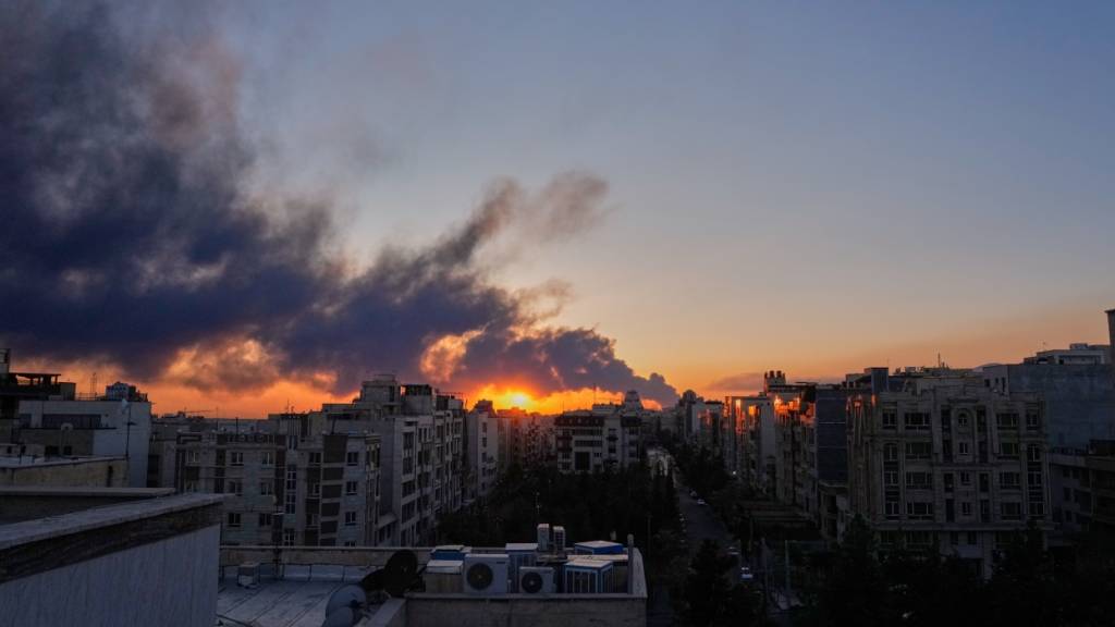 ARCHIV - Die Sonne geht hinter einer Rauchwolke unter, die nach einem amerikanisch-israelischen Militärschlag  aufsteigt. Foto: Vahid Salemi/AP/dpa