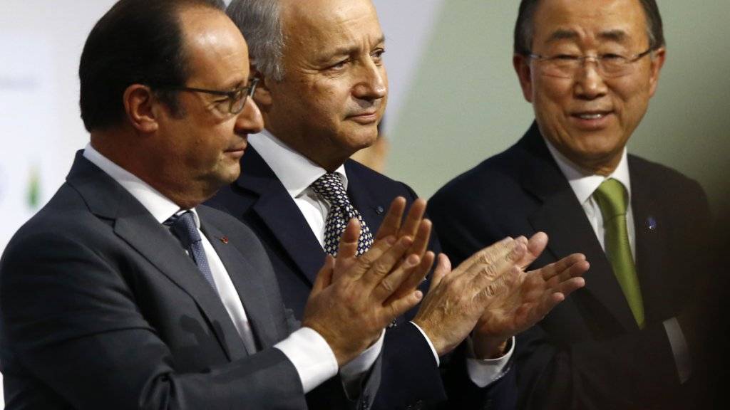 Frankreichs Präsident François Hollande, Aussenminister Laurent Fabius und UNO-Generalsekretär Ban Ki Moon applaudieren bei der Vorlage des Schlusstextes für das Klima-Abkommen.