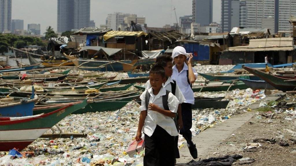 Schulkinder laufen in der philippinischen Hauptstadt Manila an einem mit Abfall verschmutzten Fluss entlang. Laut der IOM beschleunigt sich die globale Verstädterung rasant (Archiv)
