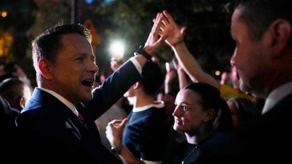 Der Präsidentschaftskandidat Rafal Trzaskowski (l), ein liberaler Befürworter der Europäischen Union, begrüßt nach der Stichwahl bei den Präsidentschaftswahlen seine Anhänger vor seinem Amtssitz. Bei der Stichwahl um das Präsidentenamt in Polen zeichnet sich nach ersten Prognosen ein Kopf-an-Kopf-Rennen ab. Auf den liberalen Kandidaten Rafal Trzaskowski entfielen demnach 50,3 Prozent der Stimmen, sein rechtskonservativer Rivale Karol Nawrocki bekam 49,7 Prozent. Foto: Petr David Josek/AP/dpa