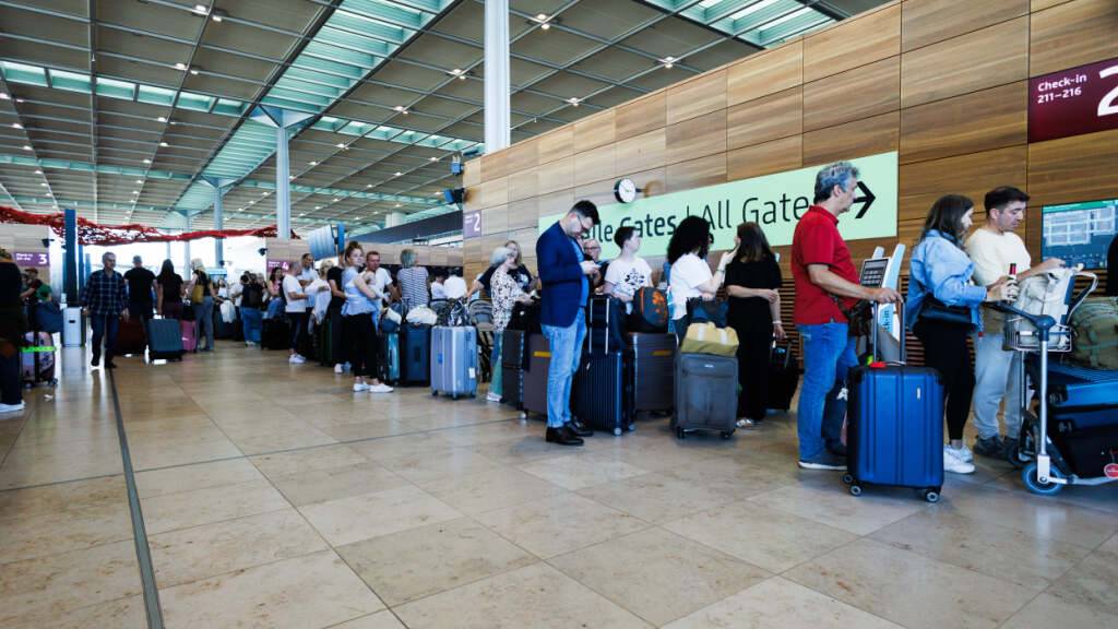 Passagiere warten in einem Terminal am Berliner Flughafen BER. Foto: Carsten Koall/dpa
