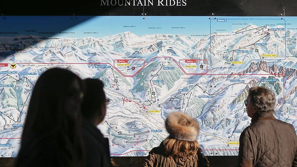 Touristen konsultieren eine Übersichtskarte der Gstaader Bergbahnen. Nach finanziellen Schwierigkeiten sind die Bahnen in den letzten Monaten saniert worden. Eine wichtige Rolle spielten dabei finanzkräftige private Investoren.