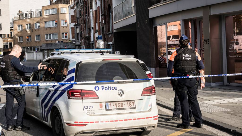 Polizisten stehen an Absperrungen und sichern ein Gebiet nach einer Explosion in der Nähe einer Synagoge in Lüttich. Foto: Valentin Bianchi/AP/dpa