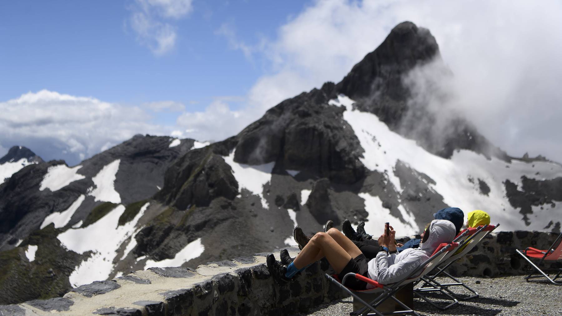 Wanderer sonnen sich bei einer Berghütte im Kanton Wallis.