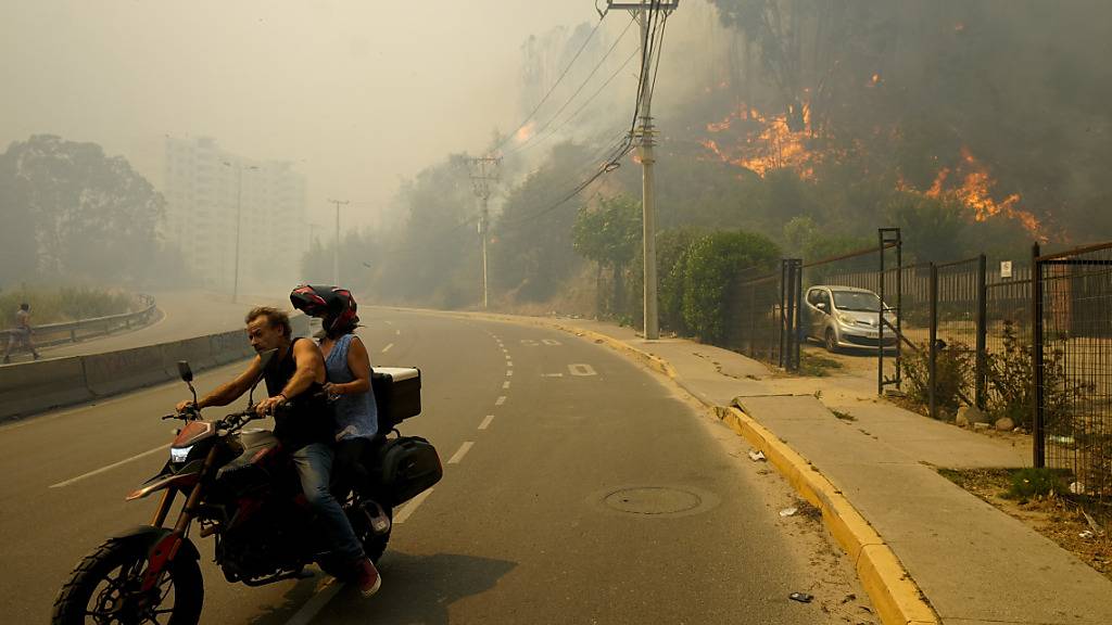 dpatopbilder - Anwohner in Chile bringen sich in Sicherheit, während der Rauch der Waldbrände den Himmel füllt. Foto: Esteban Felix/AP