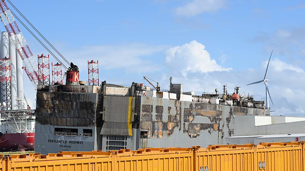 ARCHIV - Der schwer beschädigte Autofrachter »Fremantle Highway« liegt im Hafen, abgeschirmt durch gelbe Container. Foto: Lars Penning/dpa