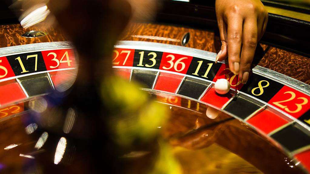 Eine Mitarbeiterin der Spielbank Stuttgart greift beim Spiel Roulette nach einer Kugel, die auf Rot liegt.
