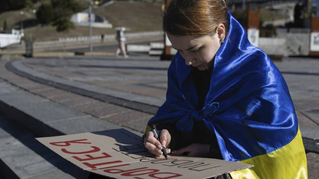 Eine Studentin in Kiew schreibt die ersten Worte des ukrainischen Gedichts «Kämpfe weiter - du wirst siegen» von Taras Schewtschenko auf ein Plakat. Foto: Alex Babenko/AP/dpa
