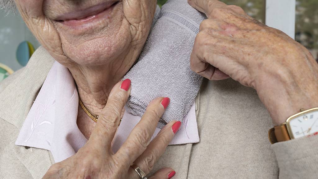 Eine ältere Frau kühlt sich wegen der Hitze den Nacken. (Archivaufname)