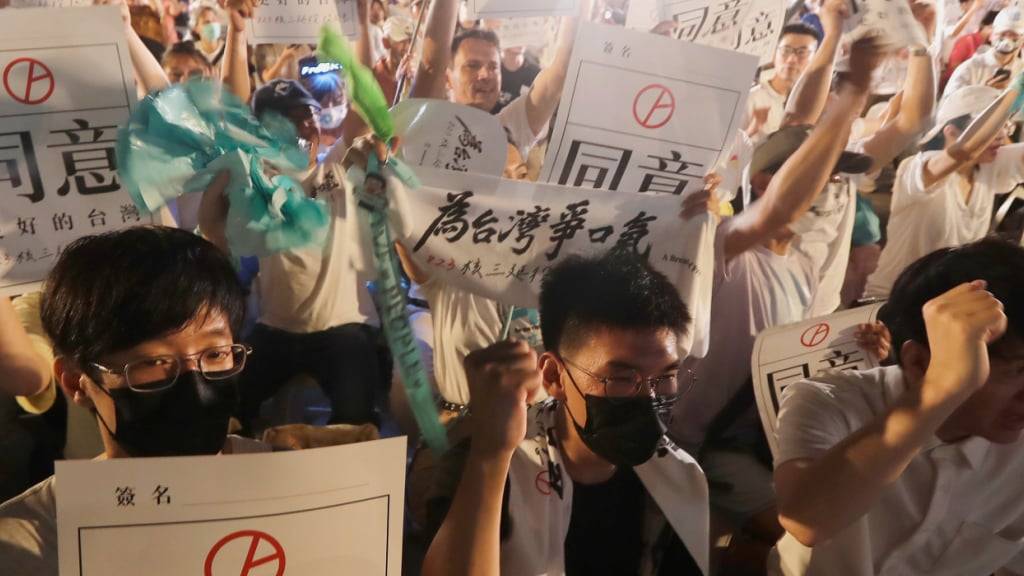 Menschen halten Schilder mit der Aufschrift «Approval» (Zustimmung), um ein Referendum zu unterstützen, das zugunsten der Verlängerung des Betriebs des dritten Kernkraftwerks in Taipeh, abgehalten wurde. Foto: ChiangYing-ying/AP/dpa