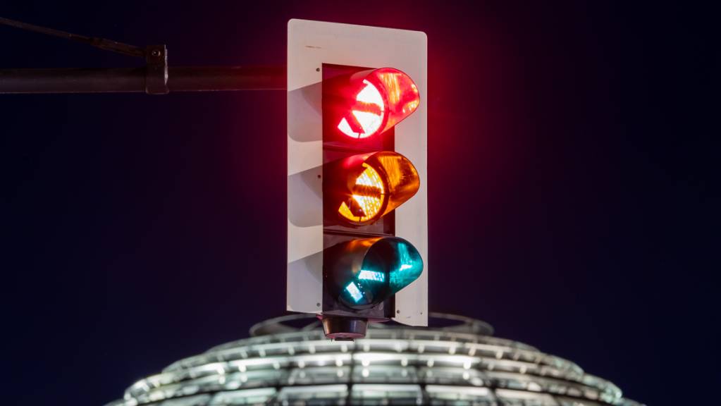 Eine Ampel vor der Kuppel des Reichstagsgebäudes leuchtet in allen drei Phasen.