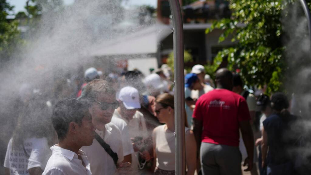 French Open-Besucher kühlen sich an einem heißen Tag mit Wasser aus Sprinklern ab. Foto: Christophe Ena/AP/dpa