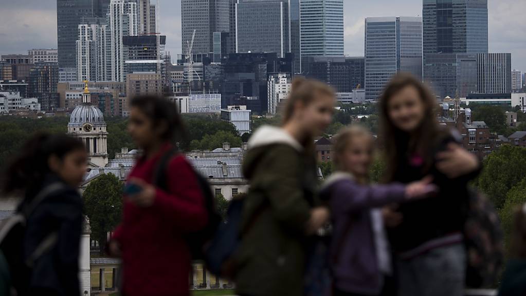 Die britische Wirtschaft hat im Januar weiter zugelegt. Touristen posieren vor der Skyline des Londoner Finanzzentrums Caranry Wharf. (Archivbild)