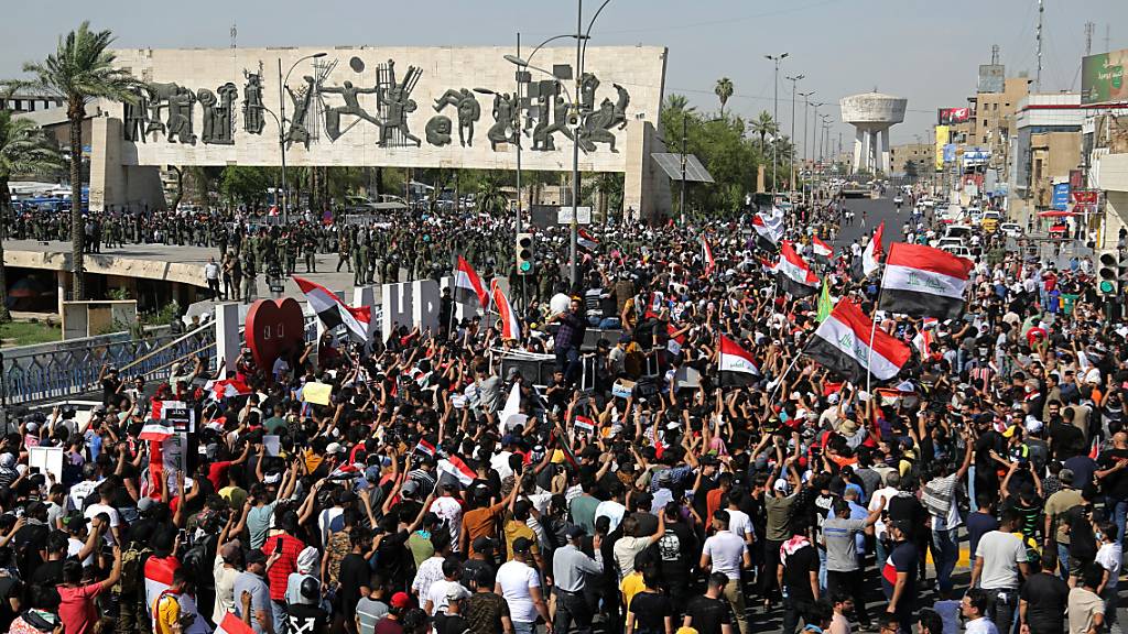 Menschen nehmen an einem regierungskritischen Protest auf dem Tahrir-Platz teil. Nach dem Tod eines bekannten politischen Aktivisten im Irak haben Tausende Demonstranten in der Hauptstadt Bagdad gefordert, die Verantwortlichen zur Rechenschaft zu ziehen. Foto: Hadi Mizban/AP/dpa Foto: Hadi Mizban/AP/dpa
