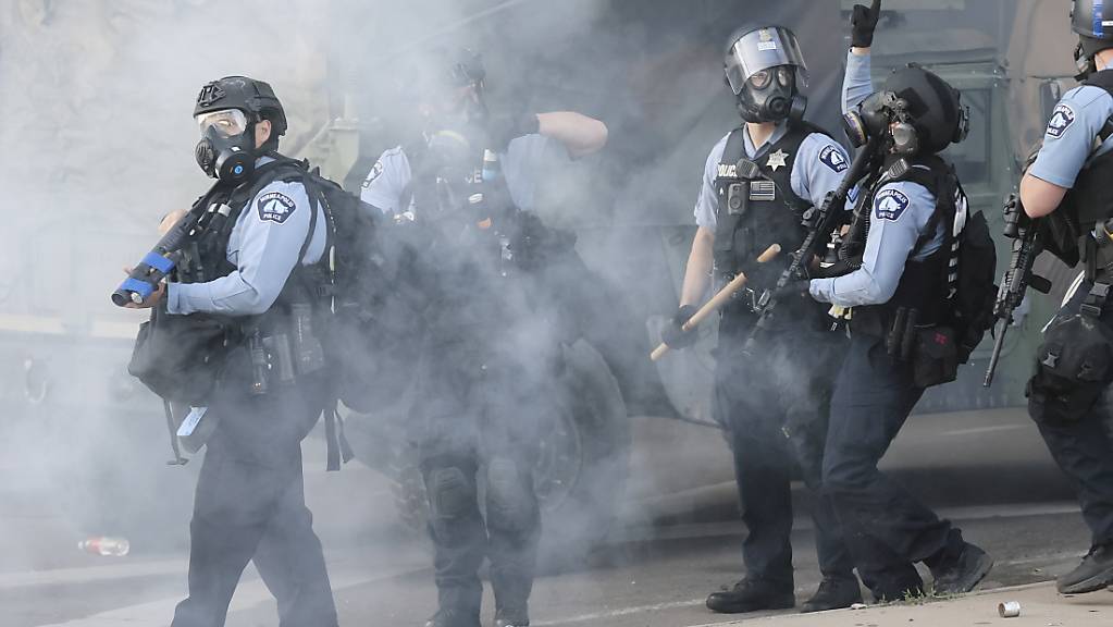 Polizisten versuchen in Minneapolis, die Proteste einzudämmen und die Ausgangssperre durchzusetzen.