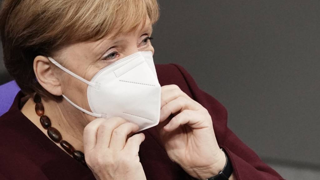 Bundeskanzlerin Angela Merkel setzt sich im Bundestag, nach der Regierungserklärung zur Bewältigung der Corona-Pandemie, ihre Maske auf. Foto: Michael Kappeler/dpa