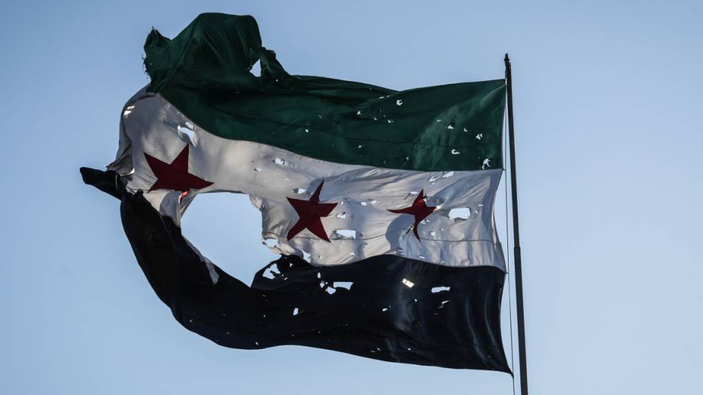 ARCHIV - Eine zerfetzte syrische Flagge weht vor dem syrischen Generalstabshauptquartier. Foto: Moawia Atrash/dpa