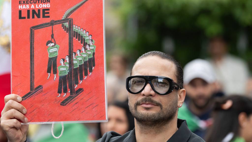 ARCHIV - Ein Mann trägt ein Schild mit der Aufschrift «In Iran, Execution has a long line». Mehrere hundert Menschen demonstrieren auf dem Rathenauplatz für den iranischen Oppositionspolitiker und Schah-Sohn Pahlavi. Auf Plakaten und in Sprechchören forderten sie ein Ende des islamischen Regimes im Iran. Foto: Boris Roessler/dpa