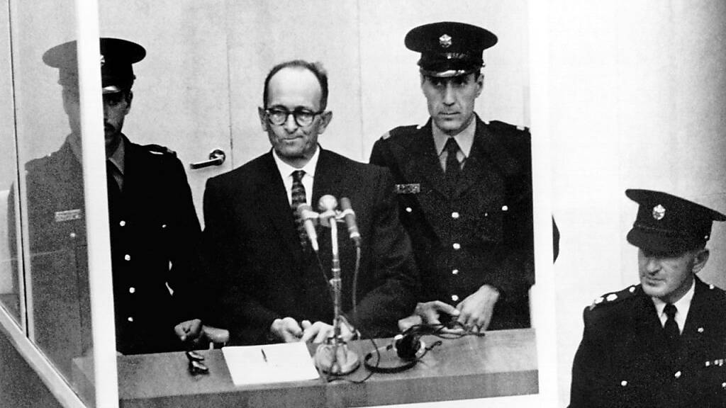 NS-Kriegsverbrecher Adolf Eichmann (2.v.l) steht während seiner Vernehmung am ersten Prozesstag vor dem Bezirksgericht in Jerusalem. Foto: picture alliance / dpa