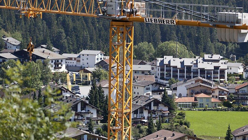 Ein Baukran über der Gemeinde Laax. Die Bautätigkeit hat in Graubünden laut einer Studie des Kantons wieder etwas Fahrt aufgenommen, ist aber immer noch zu gering für eine Entspannung auf dem knappen Wohnungsmarkt. (Archivbild)