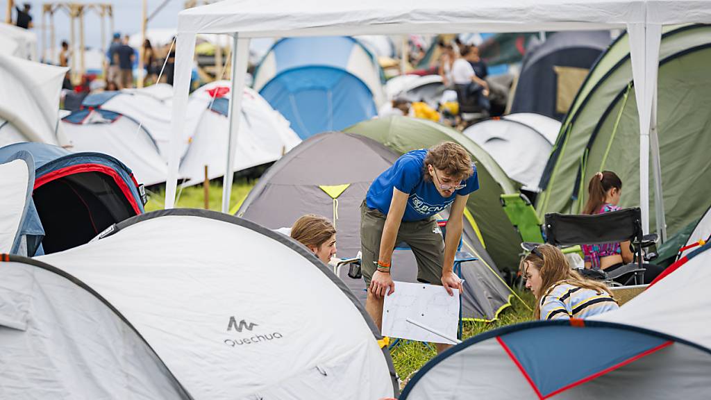 Besucherinnen und Besucher des Festival stellen in Nyon ihre Zelte auf.