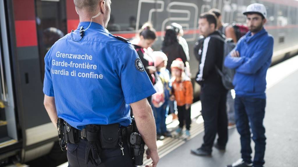 Ein Grenzwächter steht vor Fluechtlingen vor einem Railjet aus Wien, aufgenommen am Freitag, 25. September 2015, am Bahnhof in Buchs. (KEYSTONE/Gian Ehrenzeller)