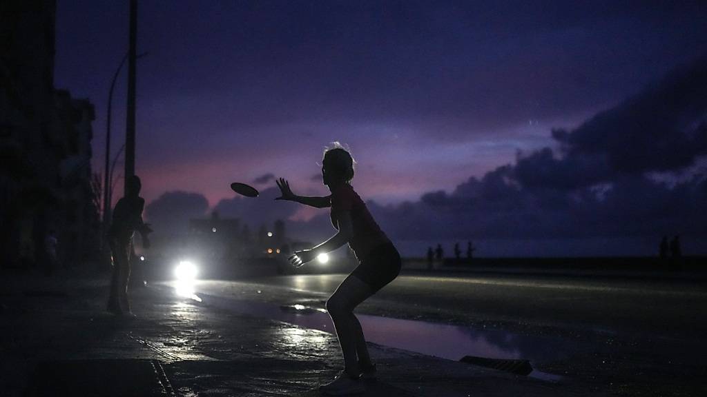 dpatopbilder - Eine Frau bereitet sich darauf vor, ein geworfenes Frisbee zu fangen, während eines Stromausfalls. Foto: Ramon Espinosa/AP/dpa