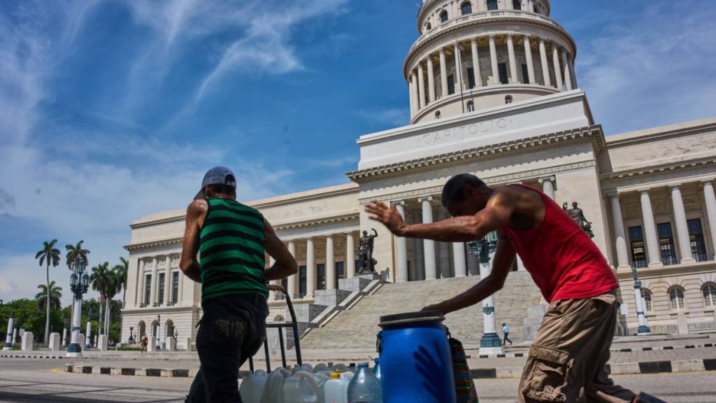 ARCHIV - Menschen tragen Wasserbehälter am Kapitol in Havanna vorbei. Foto: Ramon Espinosa/AP/dpa